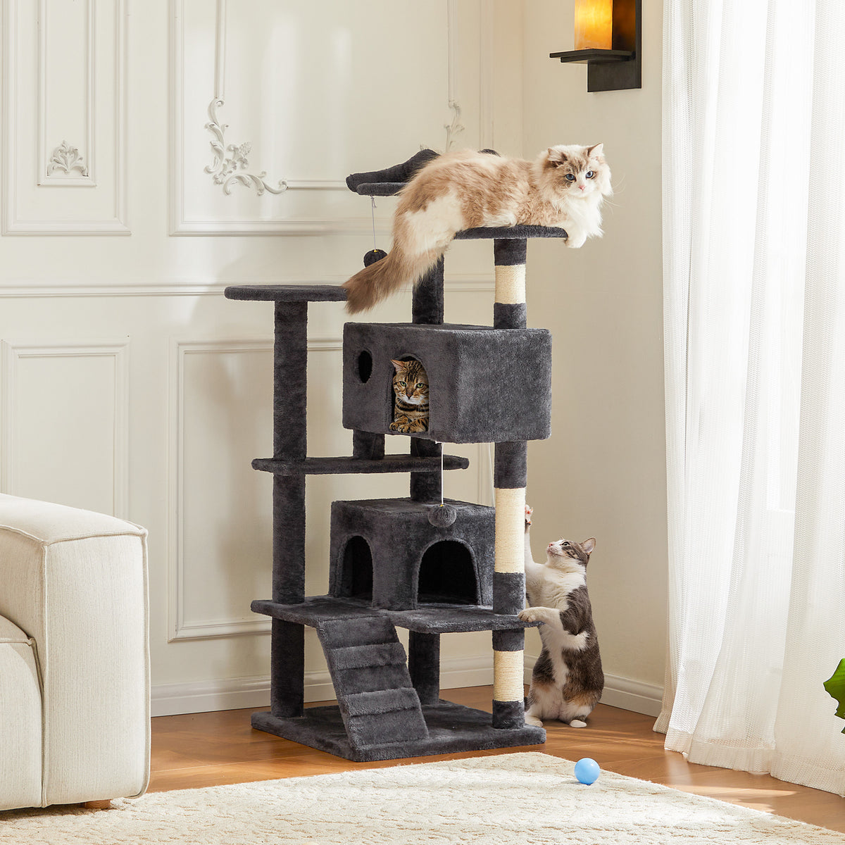 Multi-level cat tree tower with climbing cats in a cozy living room setting.
